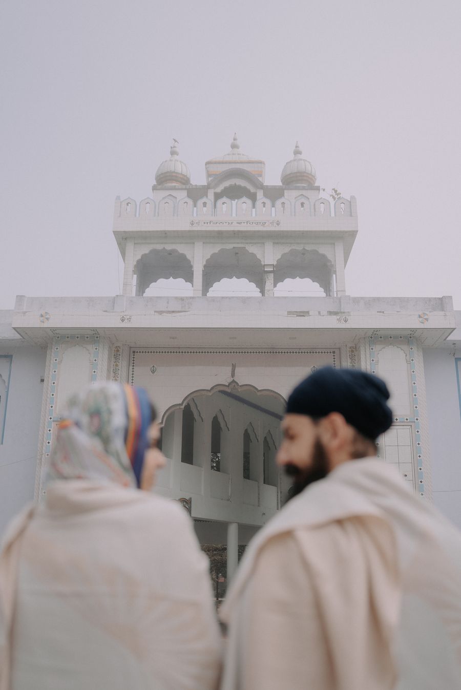 Naaz and Himmat before the white gurdwara in the fog
