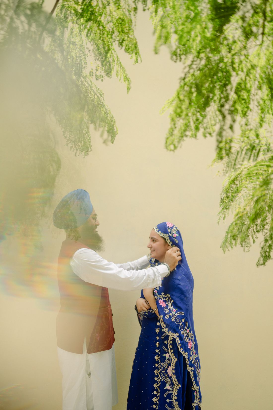 Himmat lifting the blue dupatta over Naaz under the green tree